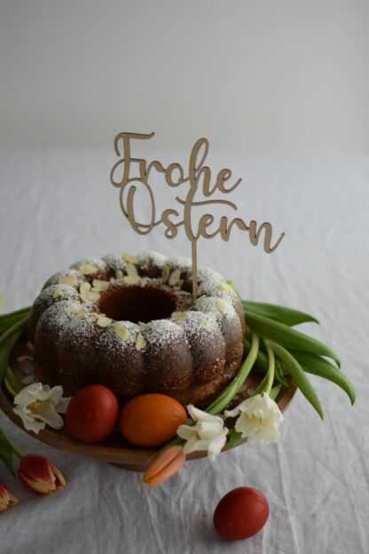 Auf dem Bild sieht man eine Torte mit einem Cake Topper mit dem Schriftzug Frohe Ostern.