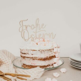 Auf diesem Bild ist eine Torte mit einem Cake Topper aus Holz mit dem Schriftzug Frohe Ostern zu sehen.