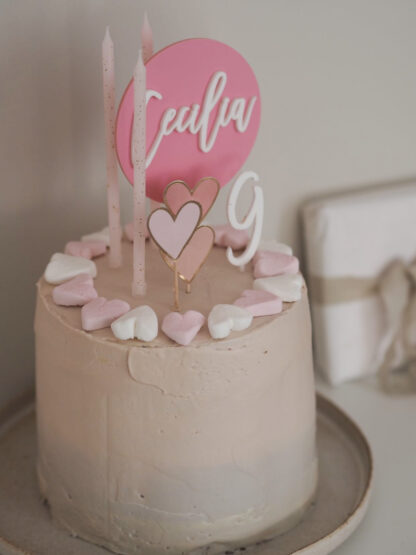 Auf dem Bild sieht man einen personalisierten Cake Topper aus Acryl, der in einer Torte steckt.