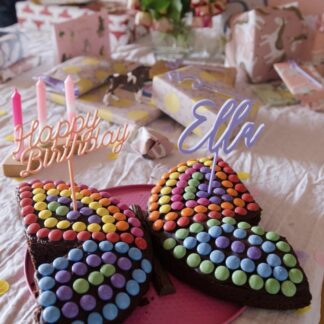 Auf diesem Bild sieht man einen Smarties Kuchen als Schmetterling mit bunten Cake Toppern.