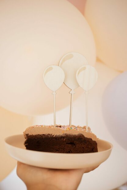 Auf diesem Bild sieht man ein Stück Kuchen mit Luftballon Cake Toppern.