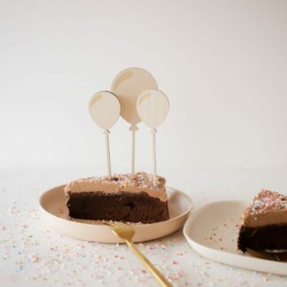 Auf diesem Bild sieht man ein Stück Kuchen mit Luftballon Cake Toppern.