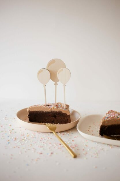 Auf diesem Bild sieht man ein Stück Kuchen mit Luftballon Cake Toppern.