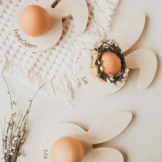 Auf dem Bild sieht man personalisierbare Eierbecher aus Holz in Form eines Hasenkopfes.