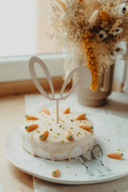 Auf dem Bild sieht man einen Rüblikuchen mit dem Cake Topper Hasenohren.