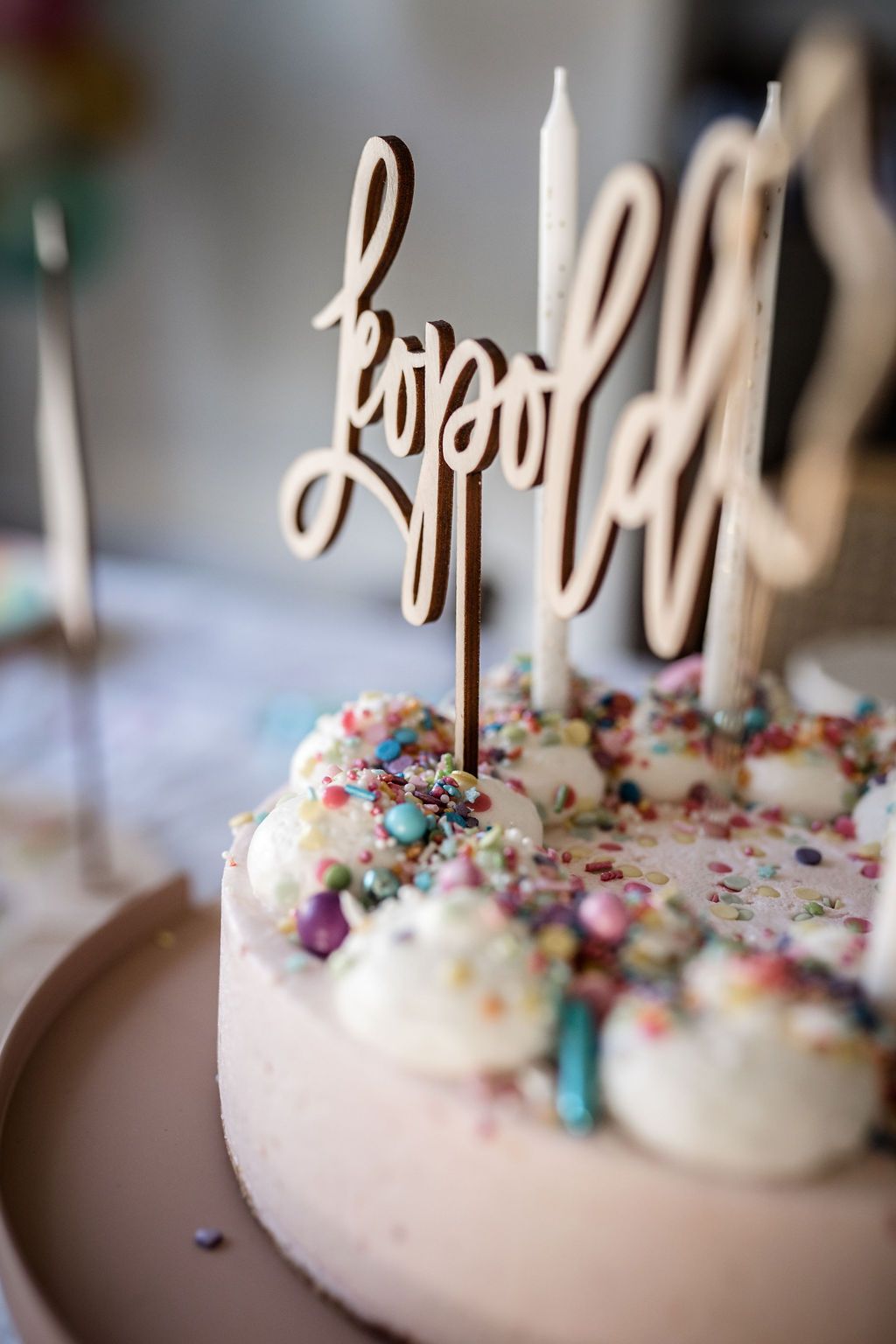 Auf diesem Bild sieht man einen Cake Topper aus Holz mit dem Namen Leopold in einem Geburtstagskuchen.