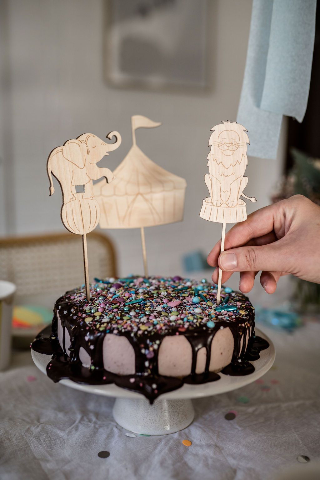 Auf diesem Bild sieht man eine Geburtstagstorte mit Cake Toppern aus Holz mit Zirkusfiguren.