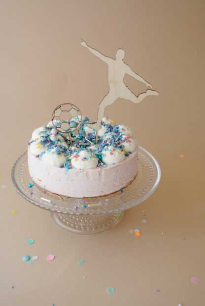 Auf diesem Bild sieht man einen Cake Topper als Fußballspieler mit einem Fußball in einer Benjamin Blümchen Torte von Coppenrath und Wiese mit Super Streuseln dekoriert.