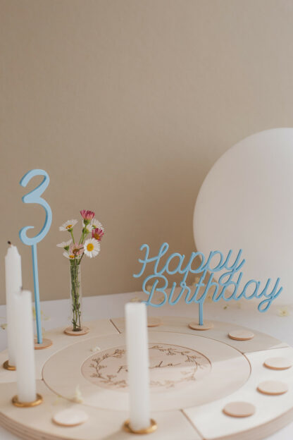 Auf diesem Bild sieht man einen Geburtstagskranz aus Holz mit blauen Steckern.