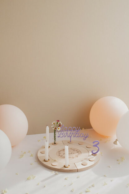 Auf diesem Bild sieht man einen Geburtstagskranz in bunt mit lila Zahlen und Happy Birthday Stecker.