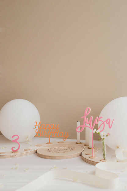 Auf diesm Bild sieht man einen Geburtstagskranz in rosa aus Holz für ein Mädchen zum dritten Geburtstag.
