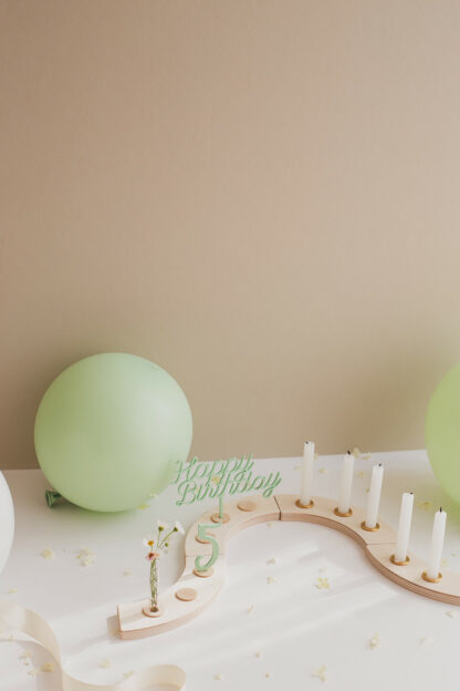 Auf diesem Bild sieht man einen bunten Geburtstagskranz in grün mit einer fünf als Stecker.