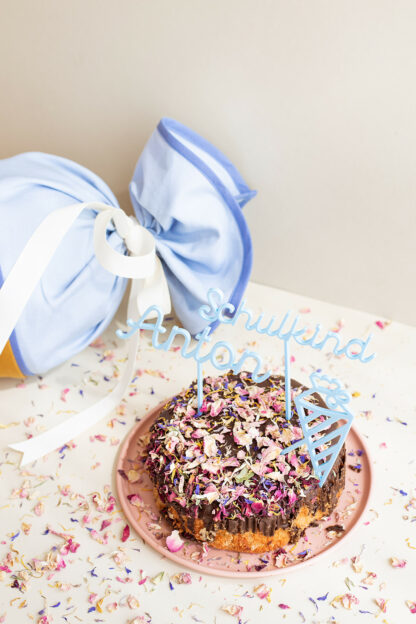 Blaue Acryl Schulkind Cake Topper mit Namen in einer Torte.