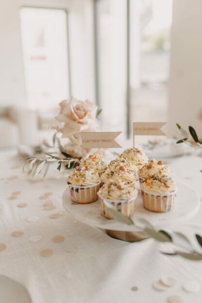 Beschriftete Cake Topper in Cupcakes stehen auf dem Geburtstagstisch.