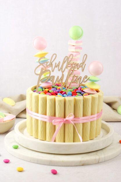 Auf diesem Bild sieht man einen Cake Topper mit einem Namen und einem mit Schulkind in einer Torte zur Einschulung.