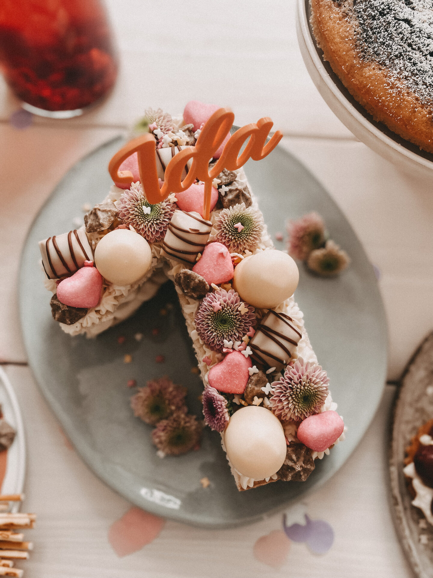 Auf dem Bild sieht man einen bunten Cake Topper mit Namen zum ersten Geburtstag in einem Kuchen.