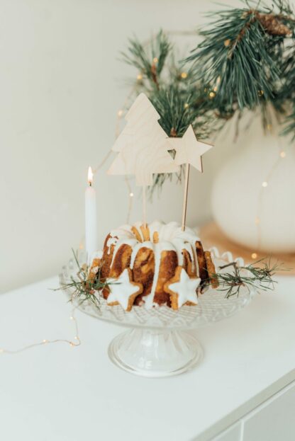 Auf diesem Bild sieht man einen Kuchen mit weihnachtlichen Cake Toppern und Zimt Sternen.