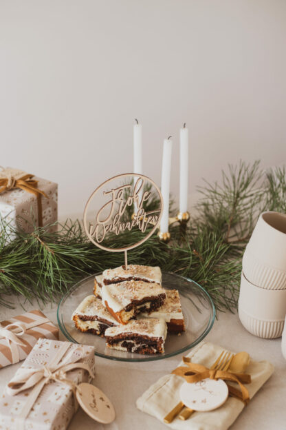 Auf diesem Bild sieht man Kuchenstücke auf einer gedeckten Tafel mit einem Frohe Weihnachten Cake Topper.