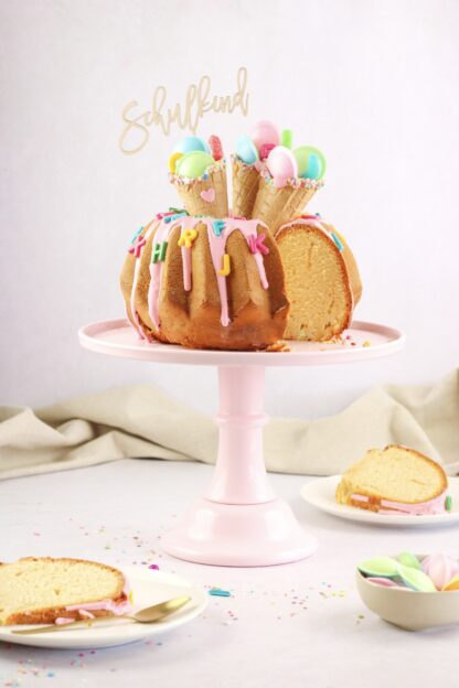Auf diesem Bild sieht man einen mit Eiswaffeln dekorierten Kuchen zur Einschulung mit einem Schulkind Cake Topper.