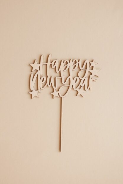 Ein Silvester Cake Topper Happy New Year aus Holz mit Sternen.