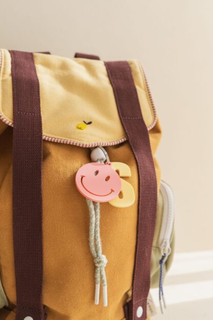 Bunte Anhänger für einen Rucksacke oder Schulranzen mit Buchstaben und einem Smiley.