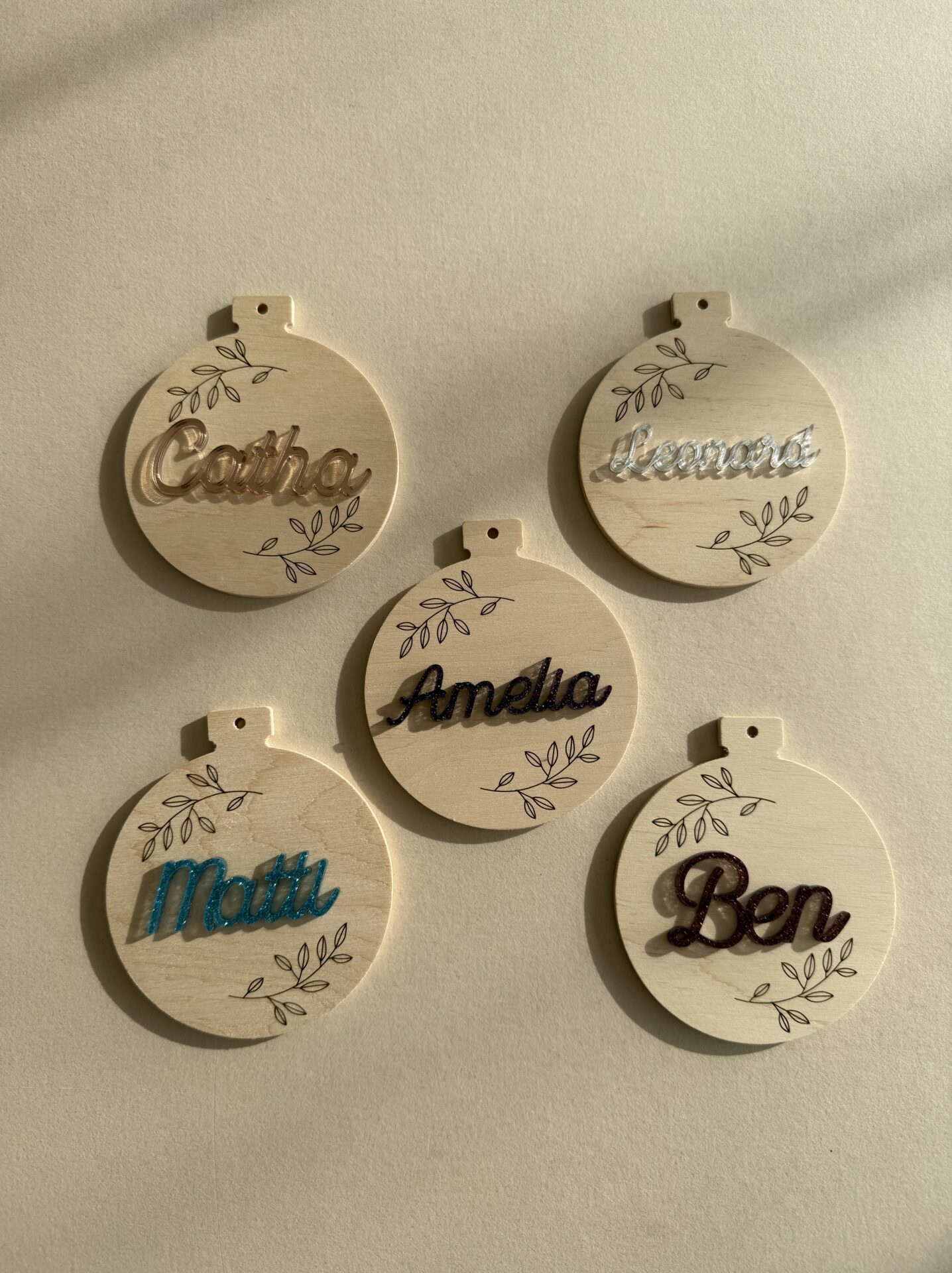 Personalisierte Weihnachtsbaumkugel aus Holz mit aufgeklebten Namen aus Acryl.